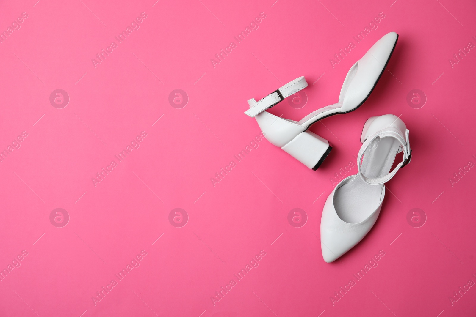 Photo of Stylish white female shoes on pink background, flat lay. Space for text