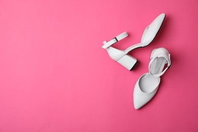 Stylish white female shoes on pink background, flat lay. Space for text