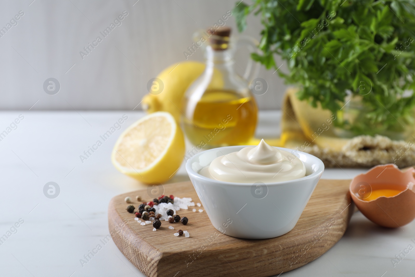 Photo of Tasty mayonnaise sauce in bowl, ingredients and spices on white table, closeup. Space for text