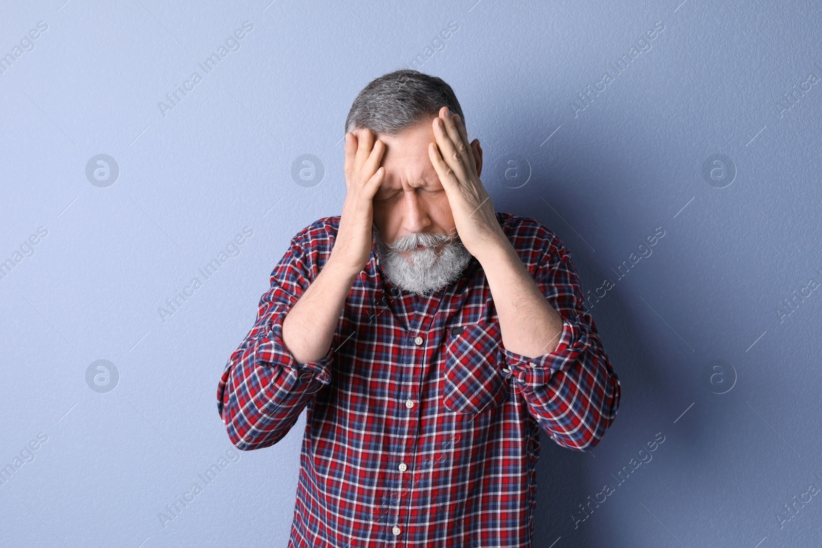 Photo of Mature man suffering from headache on color background