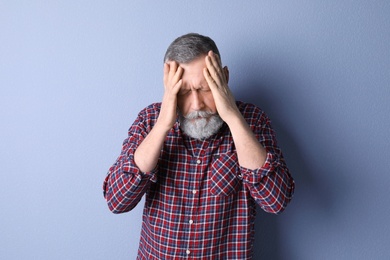 Photo of Mature man suffering from headache on color background