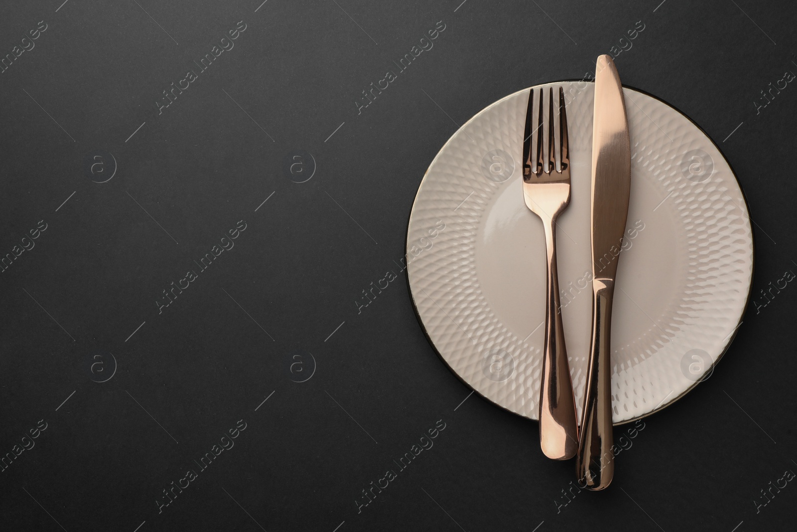 Photo of Clean plate and cutlery on black table, top view. Space for text