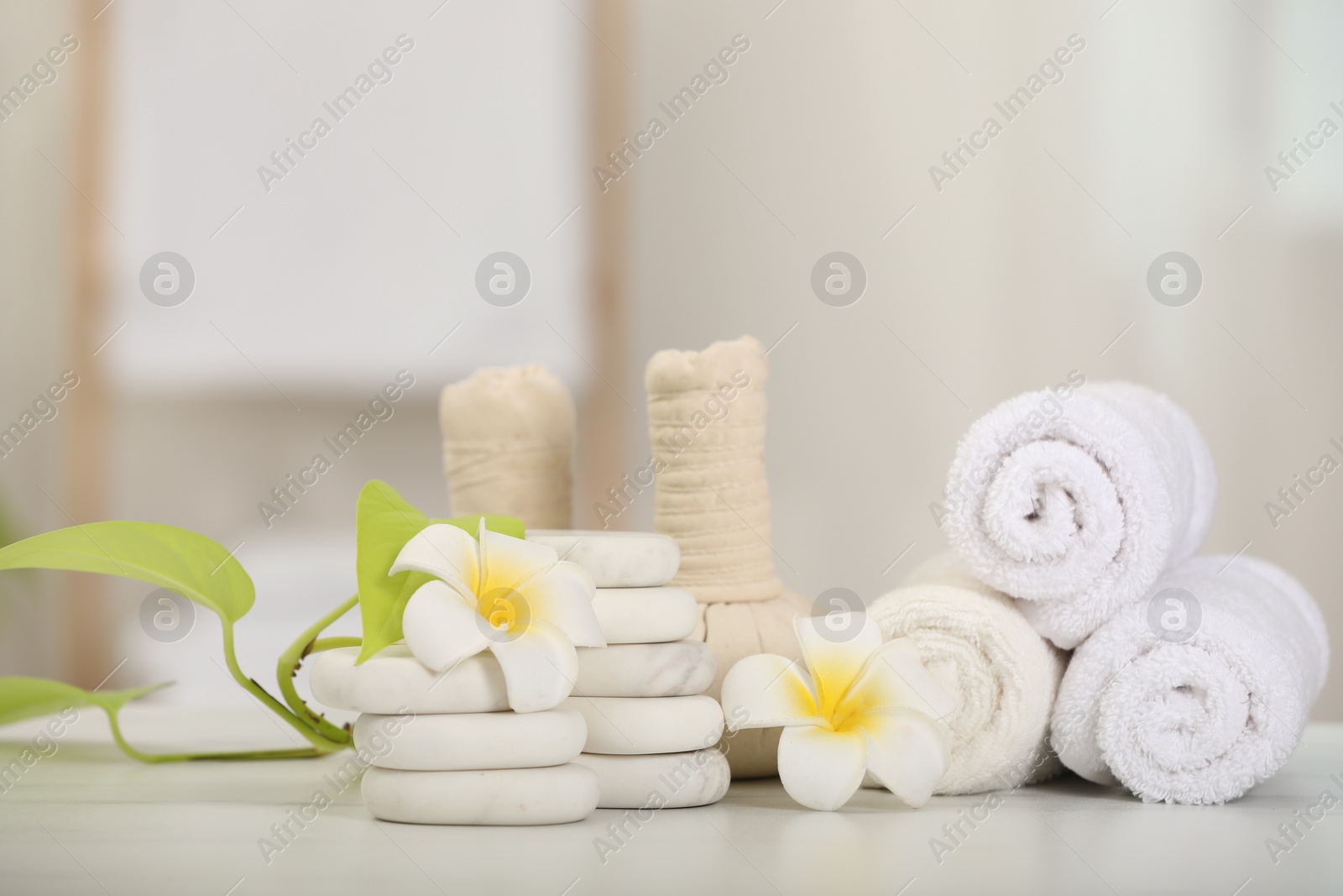 Photo of Composition with different spa products and plumeria flowers on white table