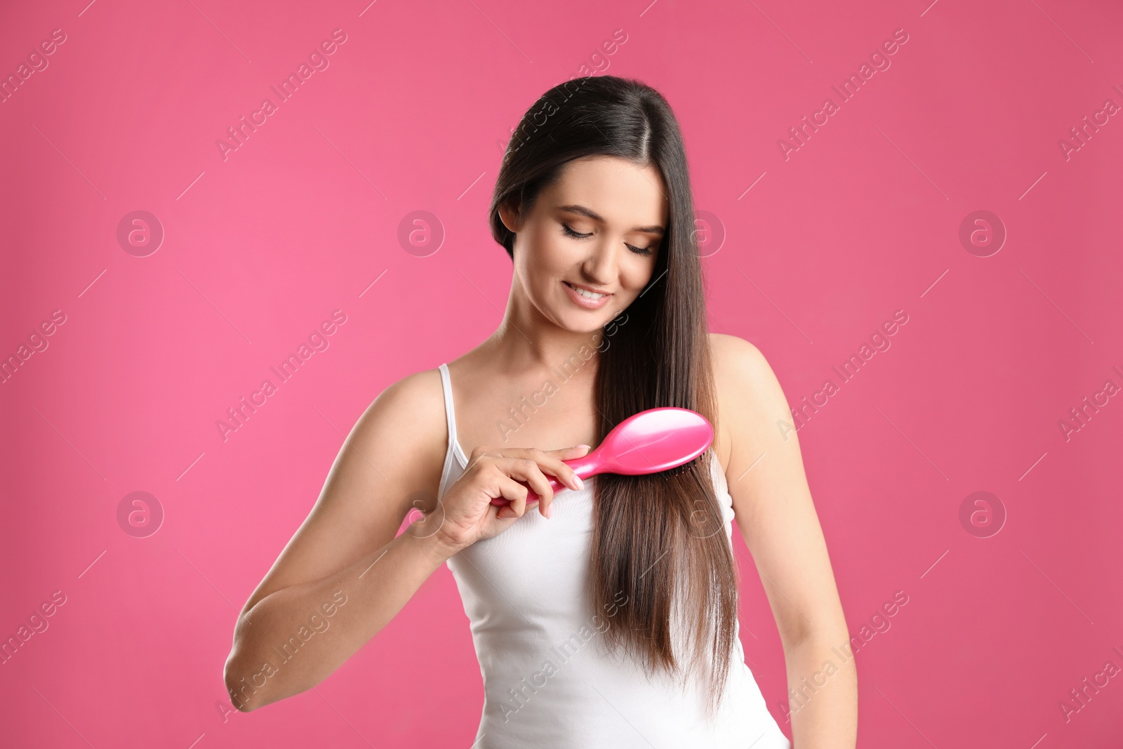 Photo of Beautiful smiling young woman with hair brush on color background