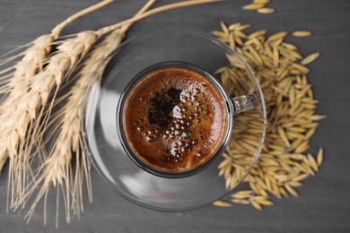 Photo of Cup of barley coffee, grains and spikes on gray table, flat lay