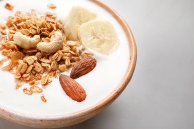 Photo of Bowl with yogurt, banana and granola on table, closeup