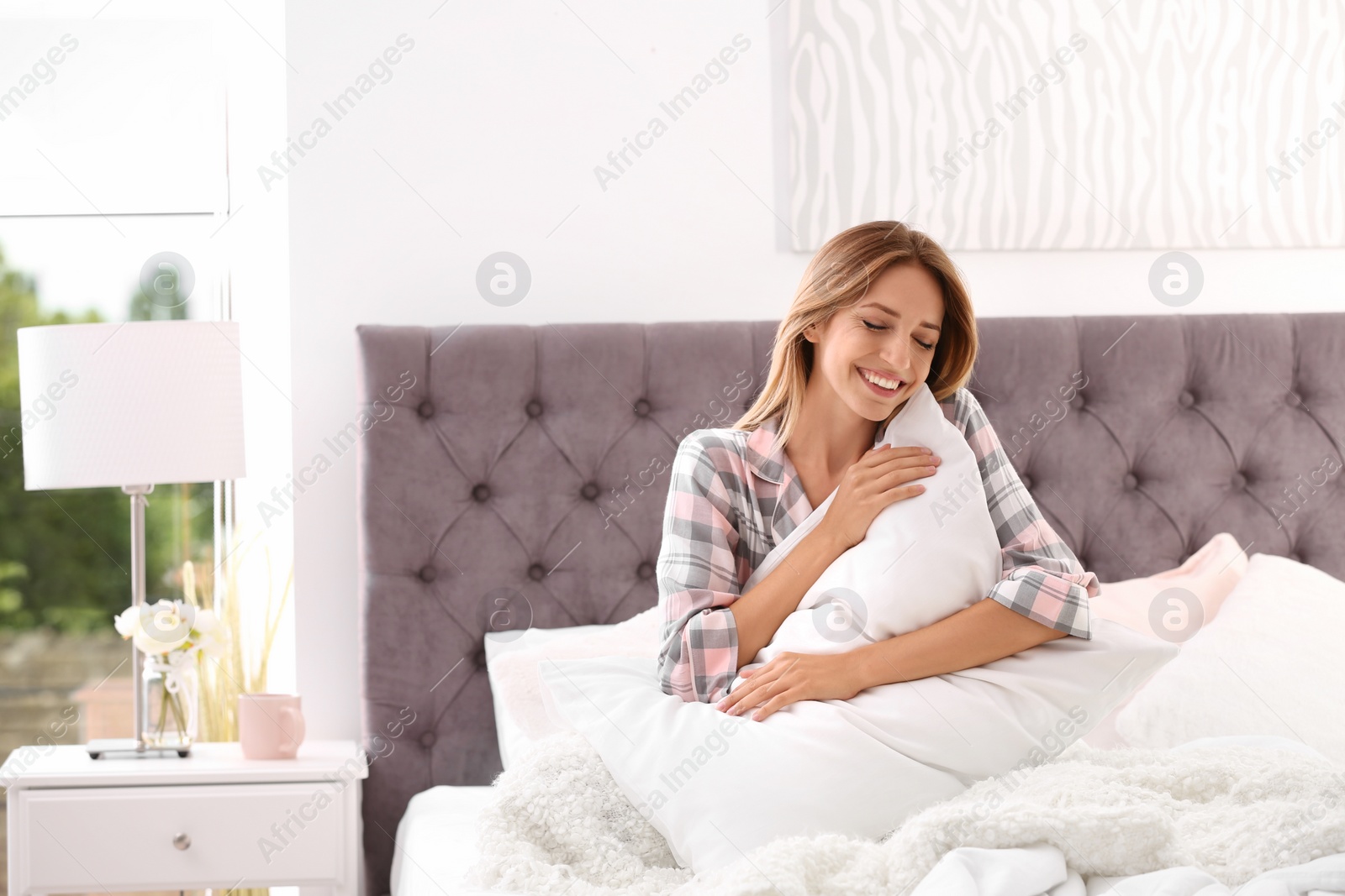 Photo of Young woman embracing pillow in bed at home. Peaceful morning