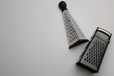 Modern graters on grey background, flat lay. Space for text