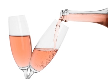 Pouring rose champagne from bottle into glass on white background