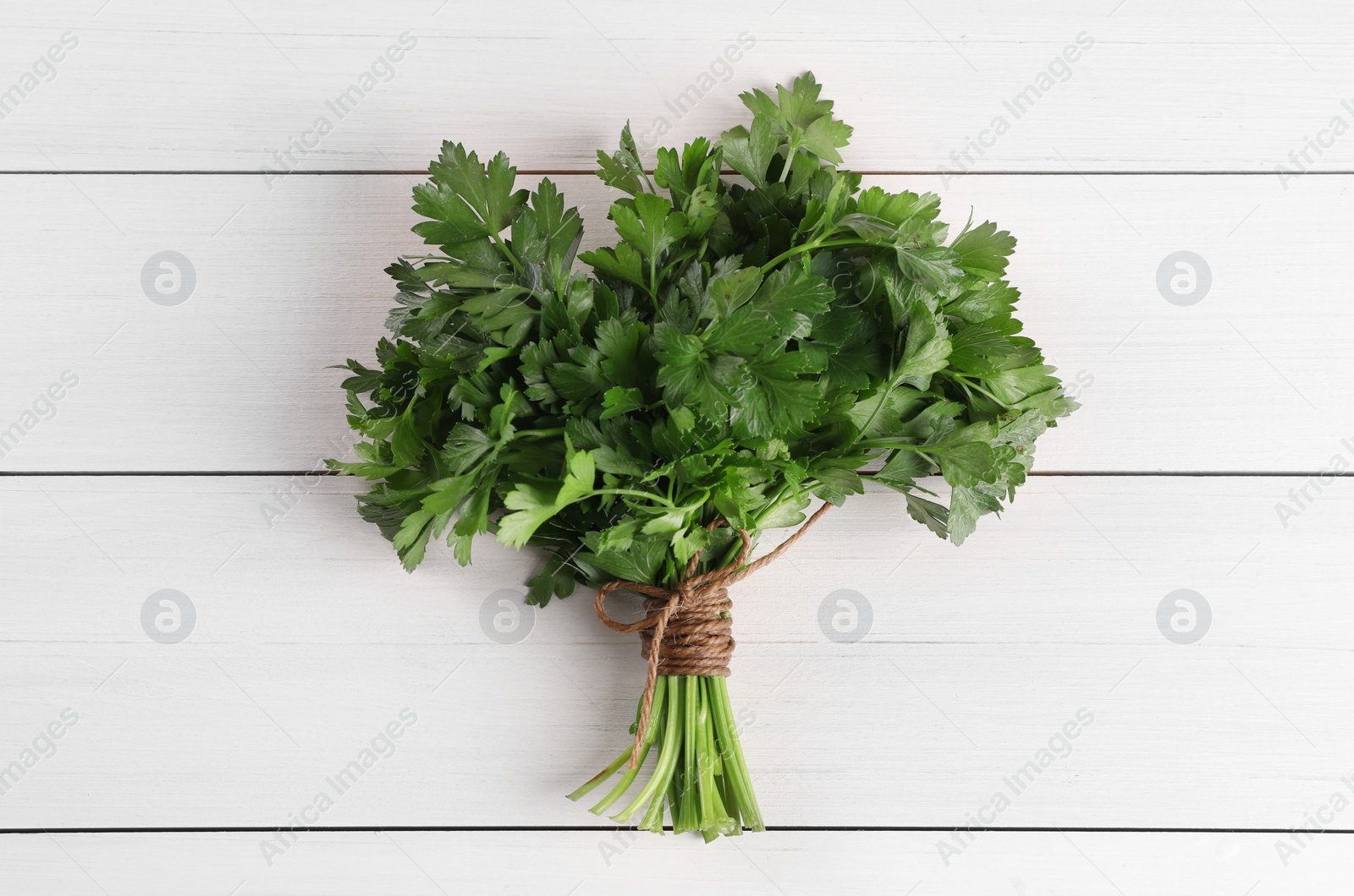 Photo of Bunch of fresh parsley on white wooden table, top view