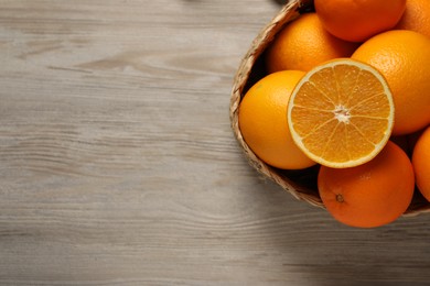 Many whole and cut oranges on wooden table, top view . Space for text