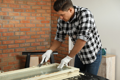 Photo of Man repairing old damaged window at table indoors