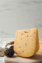 Photo of Delicious cheese and fresh black truffles on table. Space for text