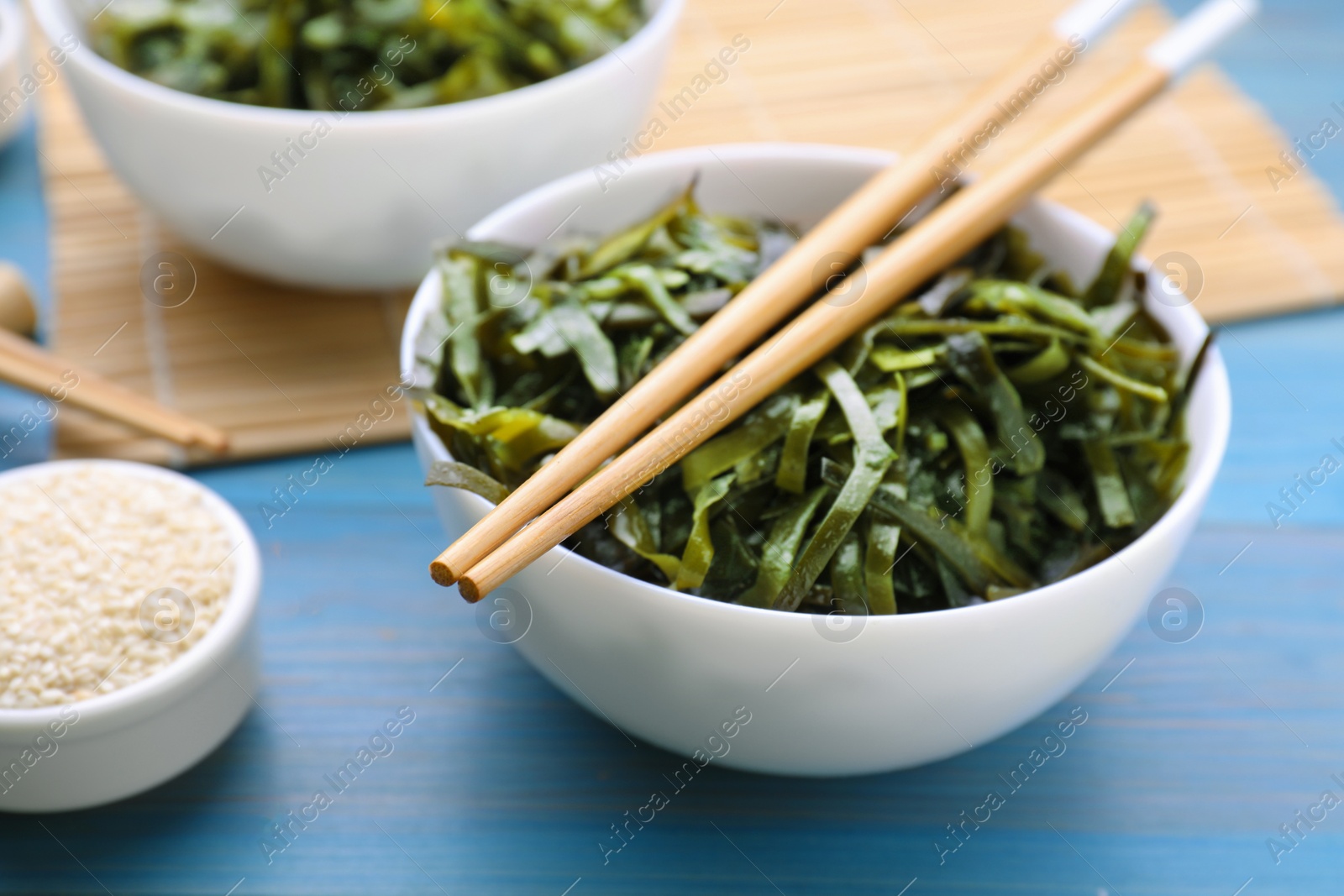 Photo of Fresh laminaria (kelp) seaweed served on light blue wooden table, closeup