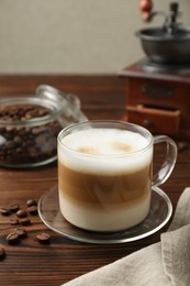 Aromatic coffee in cup and beans on wooden table