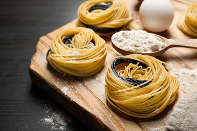 Photo of Raw linguine pasta on black wooden table, closeup