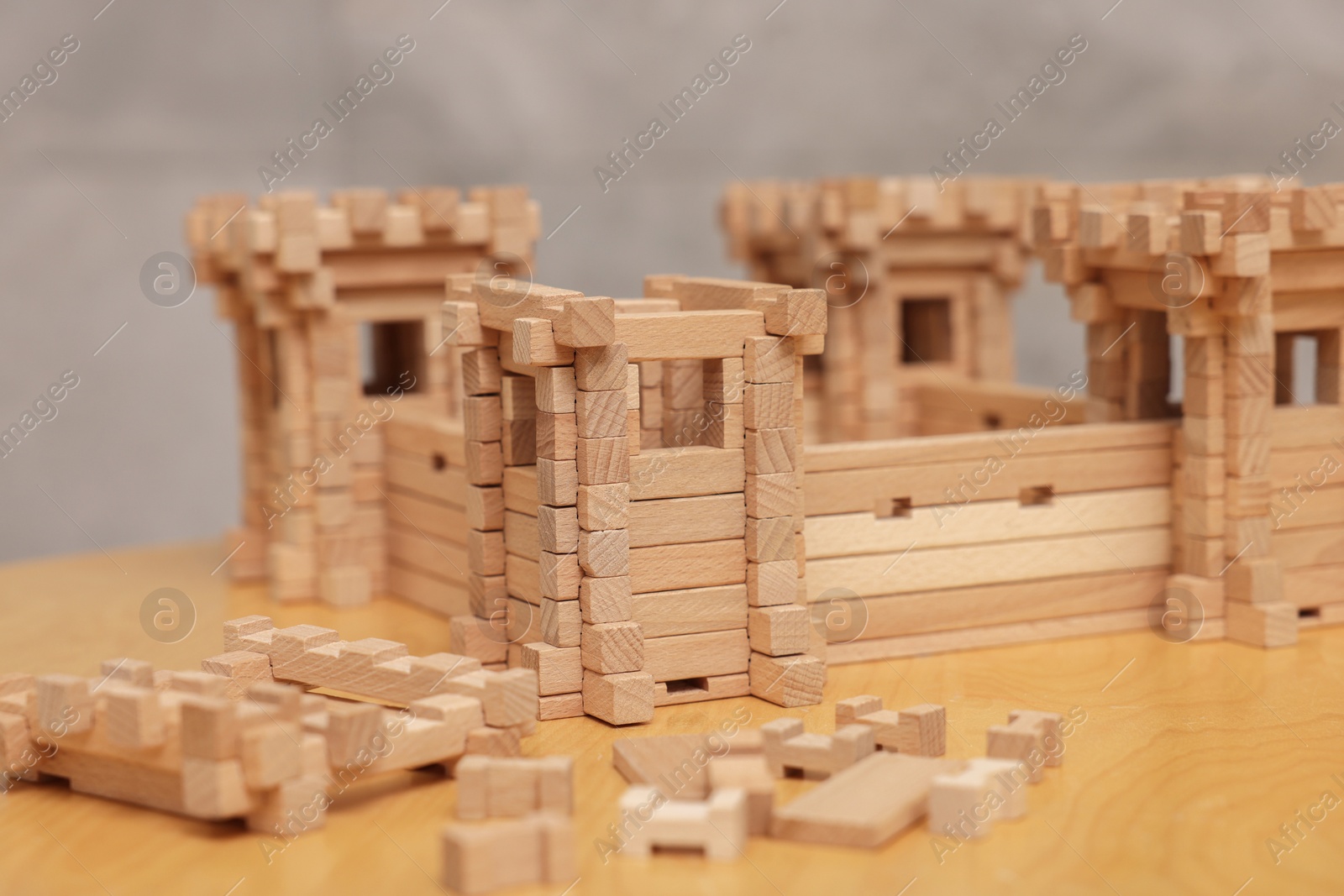 Photo of Wooden fortress and building blocks on table against grey background, closeup. Children's toy