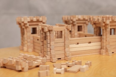 Wooden fortress and building blocks on table against grey background, closeup. Children's toy