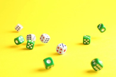 Photo of Many color game dices falling on yellow background