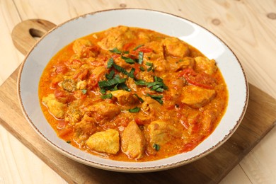 Photo of Delicious chicken curry on wooden table, closeup