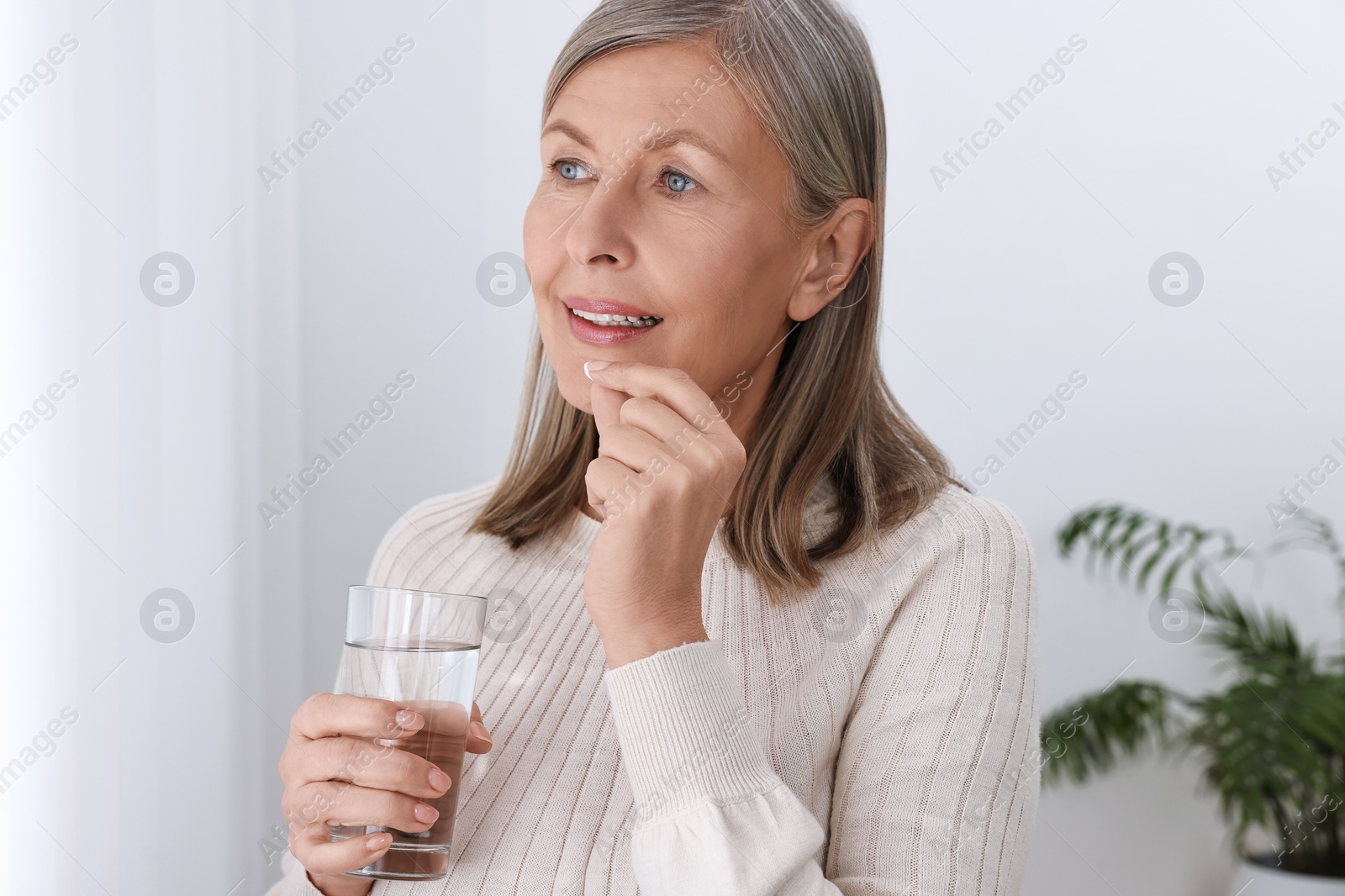 Photo of Beautiful woman taking vitamin pill at home