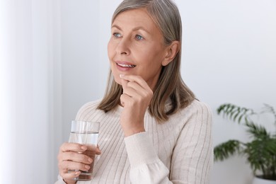 Beautiful woman taking vitamin pill at home