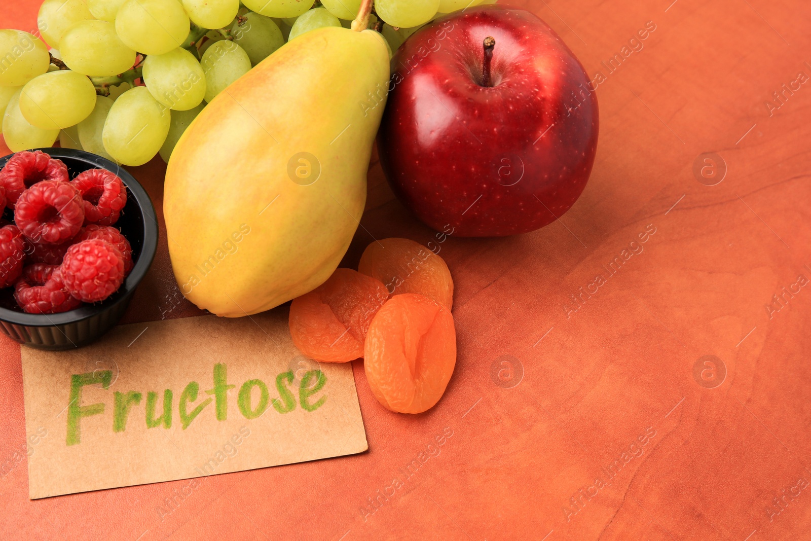 Photo of Card with word Fructose, delicious ripe fruits, raspberries and dried apricots on wooden table, closeup