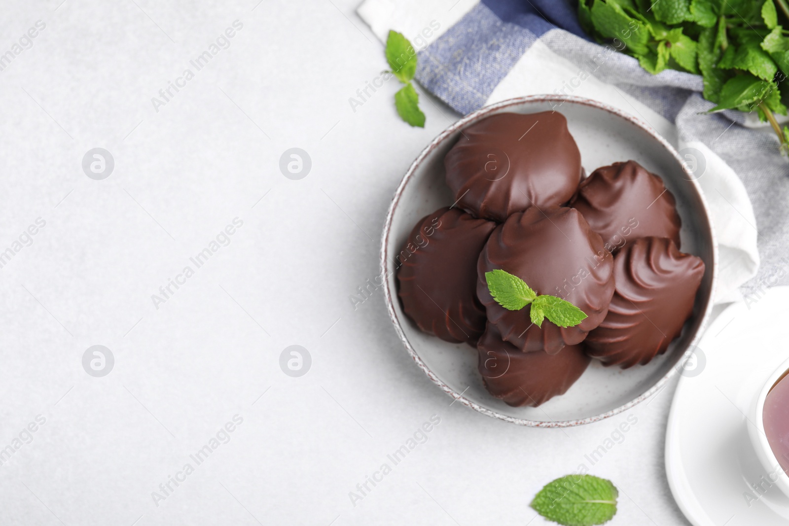 Photo of Delicious chocolate covered zephyrs and mint on white table, flat lay. Space for text