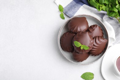 Photo of Delicious chocolate covered zephyrs and mint on white table, flat lay. Space for text