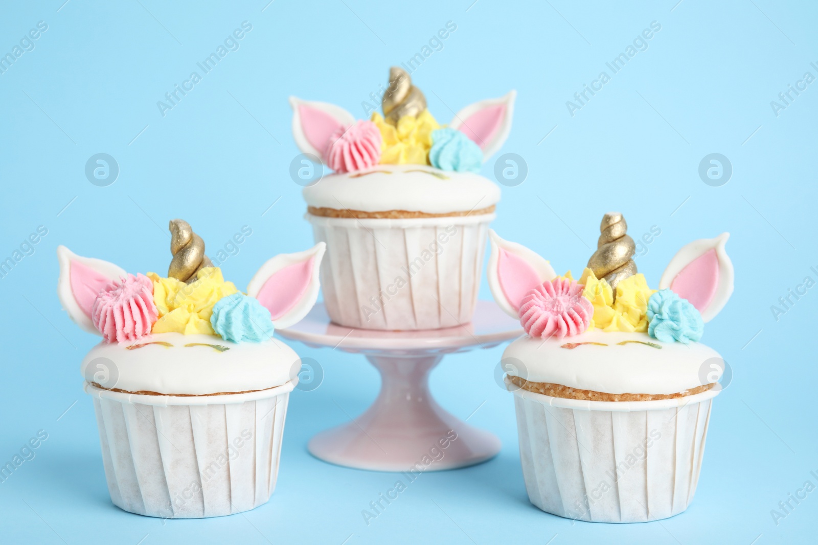 Photo of Cute sweet unicorn cupcakes on light blue background