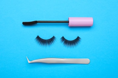Photo of Flat lay composition with fake eyelashes, mascara brush and tweezers on light blue background