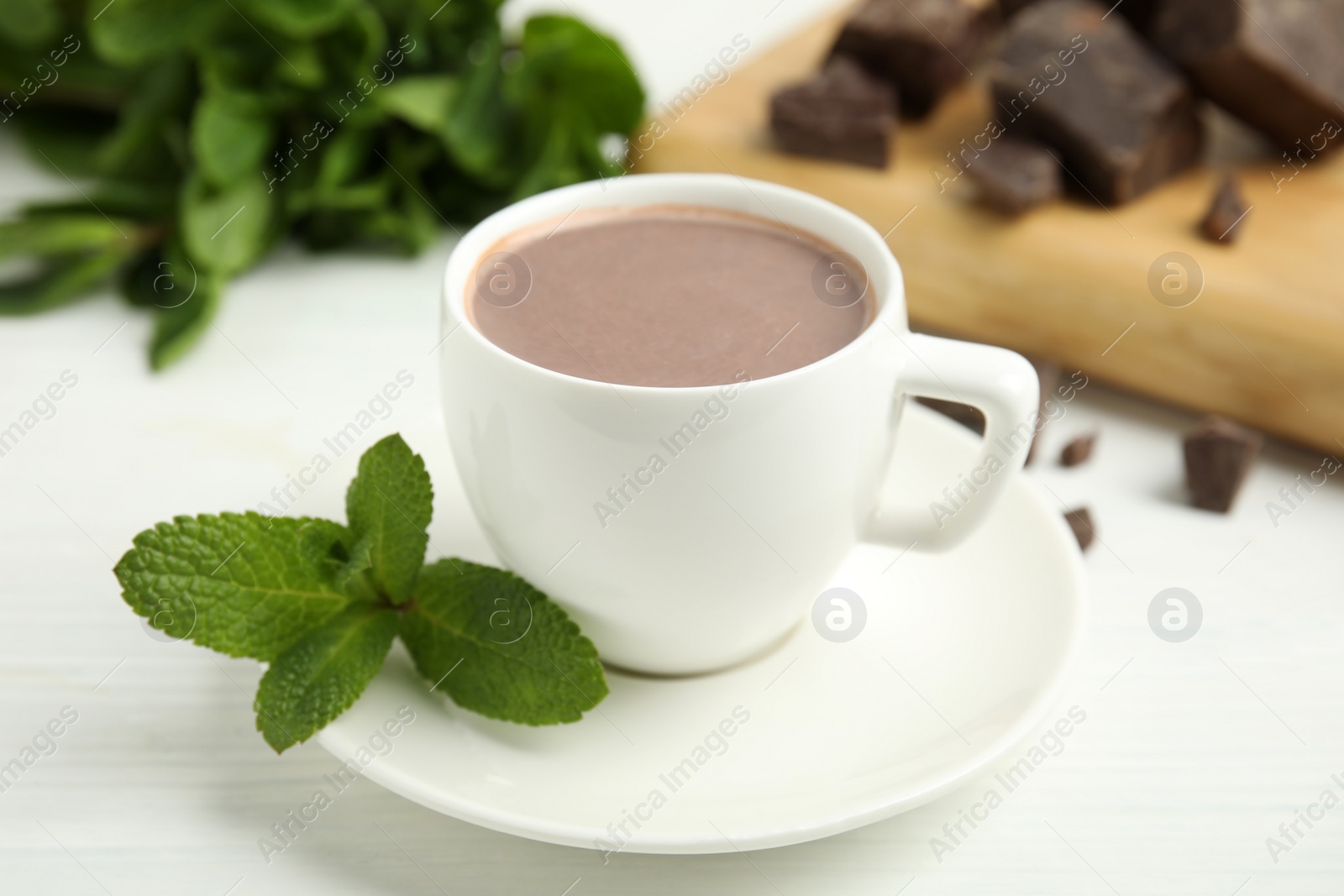 Photo of Cup of delicious hot chocolate and fresh mint on white wooden table