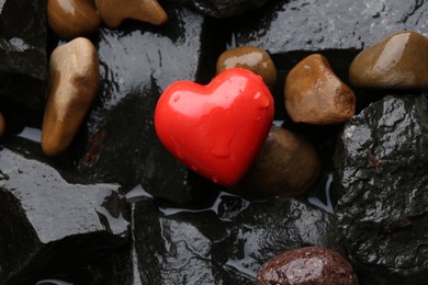 Red decorative heart on stones and water, top view