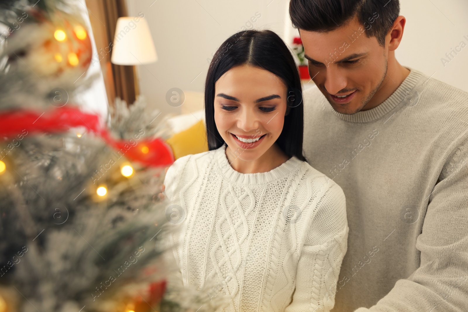 Photo of Happy couple decorating Christmas tree at home