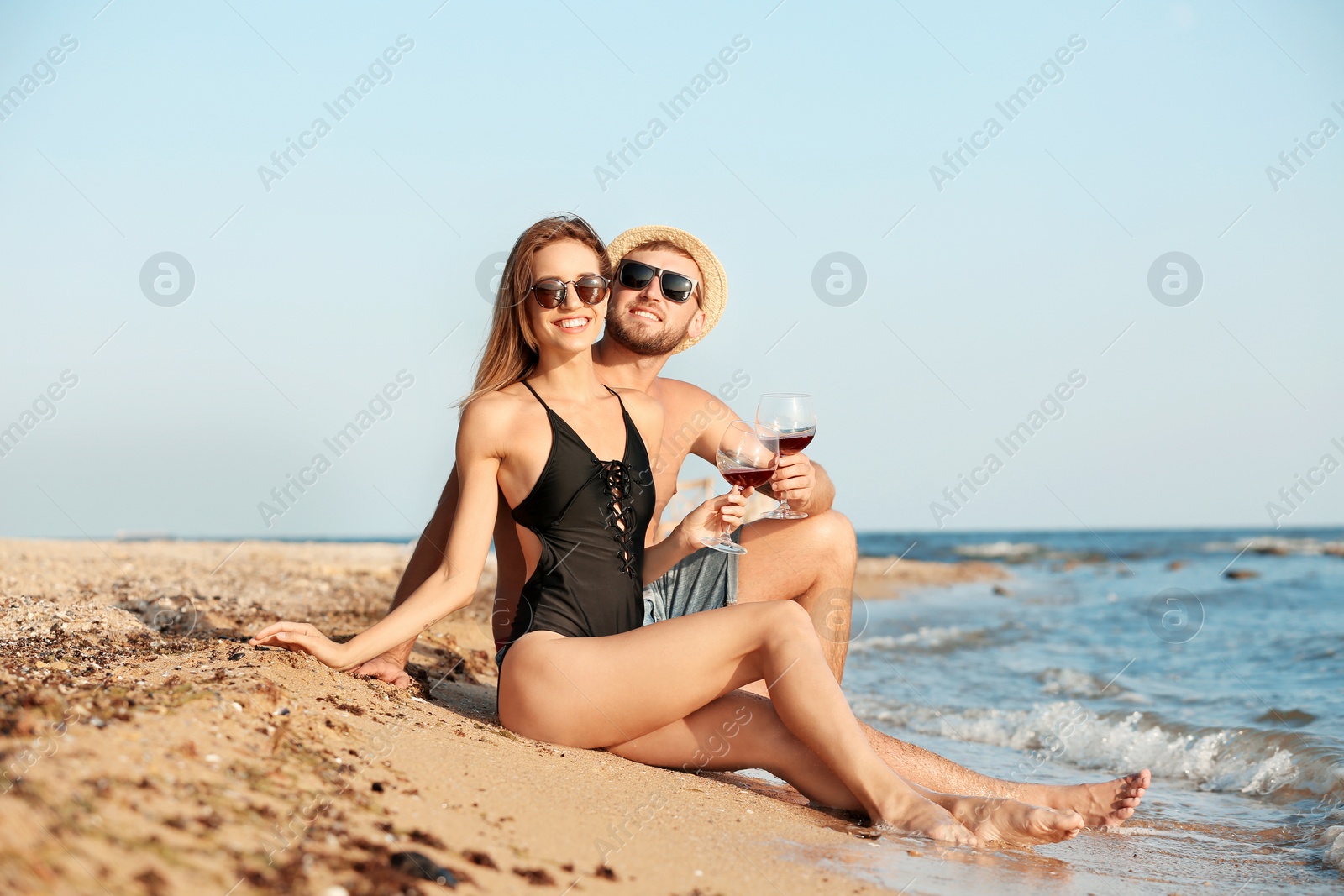 Photo of Young couple with glasses of wine on beach