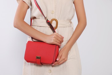 Photo of Woman with stylish red bag on light grey background, closeup