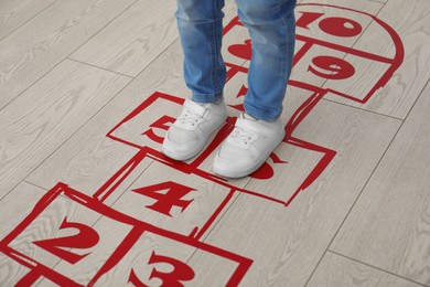 Little girl playing hopscotch at home, closeup