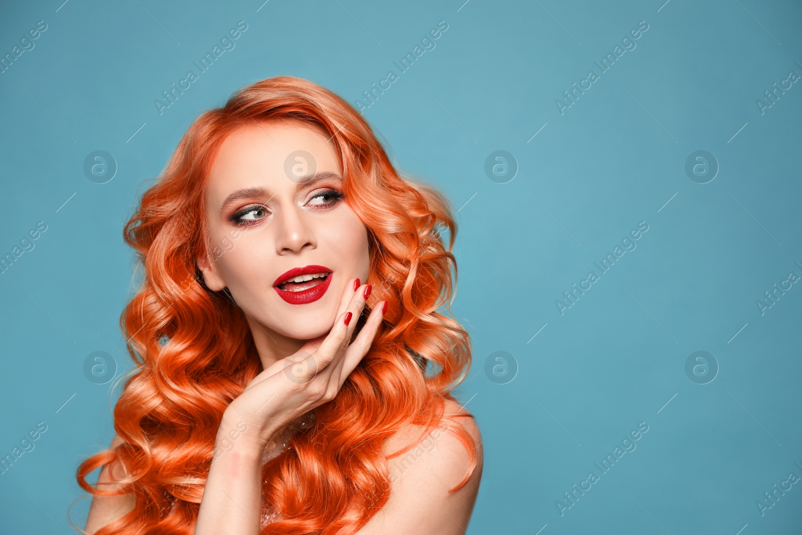 Image of Beautiful woman with long orange hair on light blue background