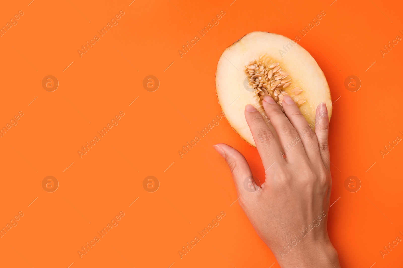 Photo of Young woman touching half of melon on orange background, top view with space for text. Sex concept