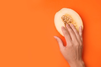 Photo of Young woman touching half of melon on orange background, top view with space for text. Sex concept