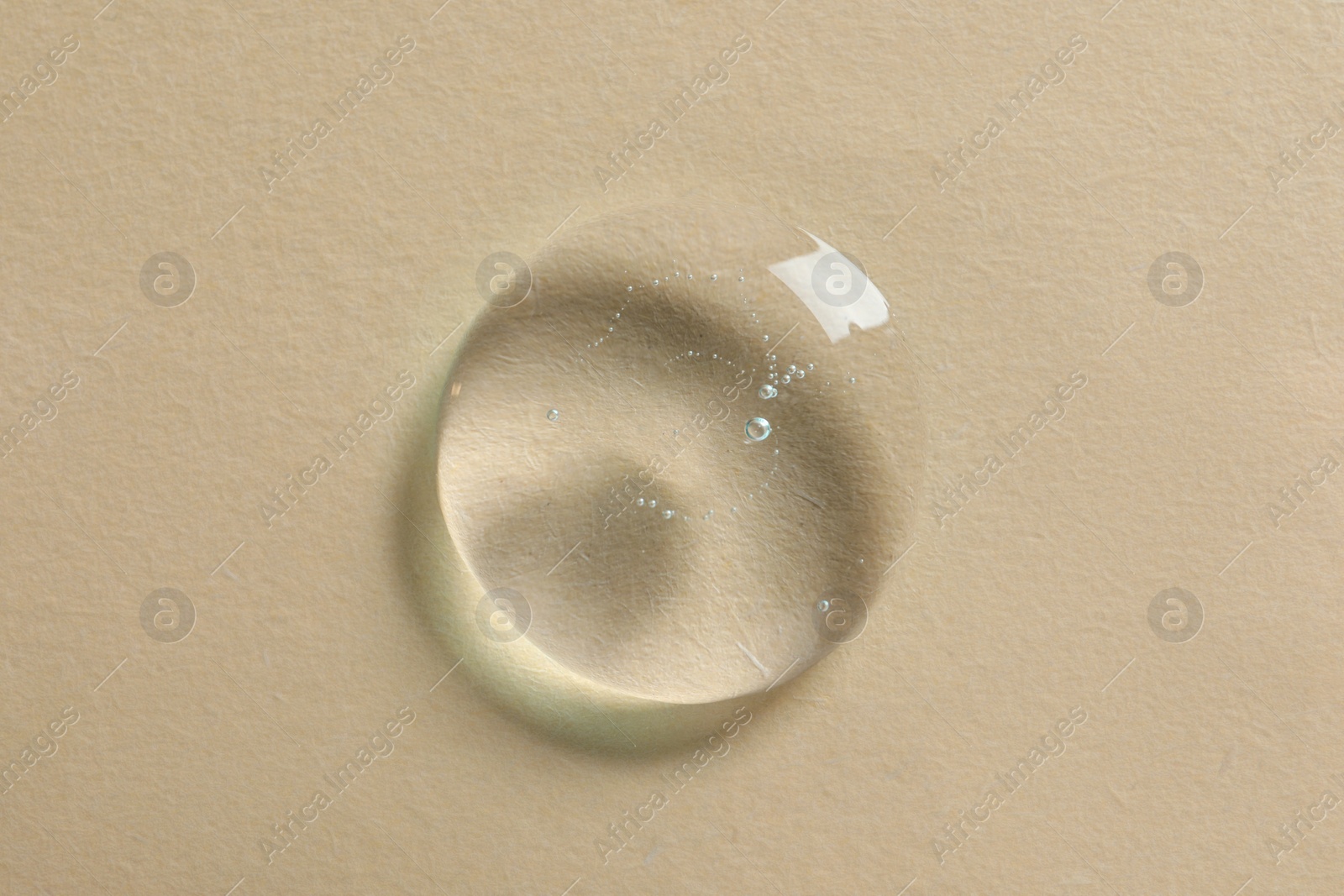 Photo of Drop of cosmetic oil on beige background, top view