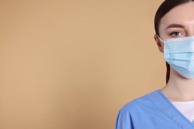 Photo of Nurse wearing protective mask on light brown background, closeup. Space for text