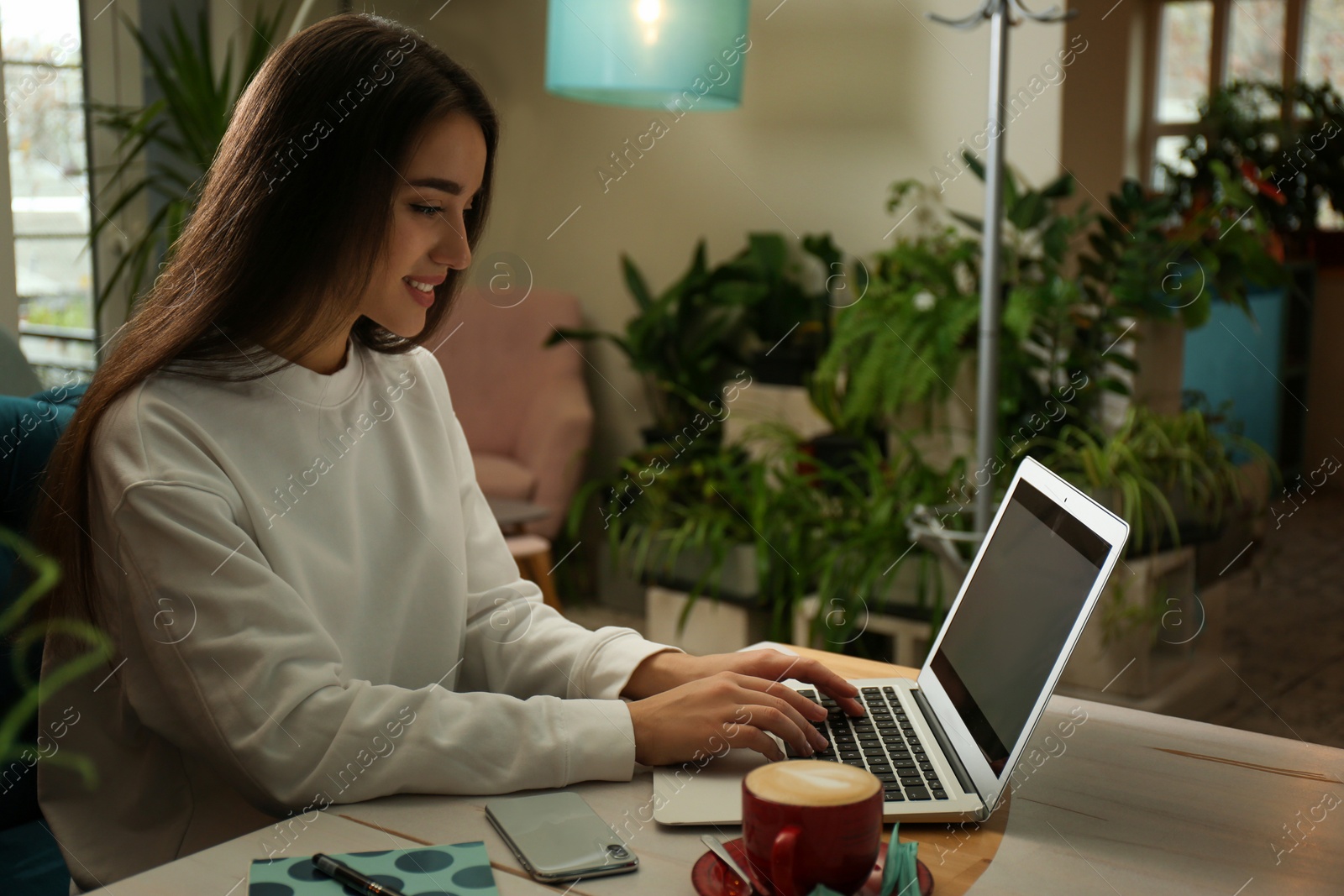 Photo of Young blogger working with laptop in cafe