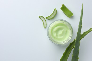 Photo of Jar of natural cream and cut aloe leaves on white background, flat lay. Space for text