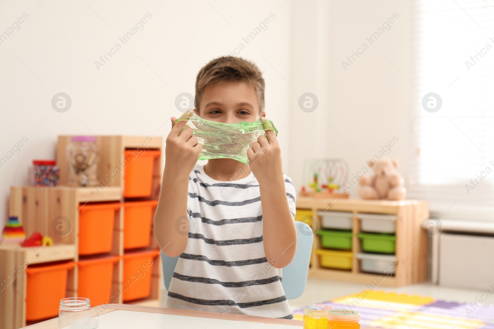 Photo of Little boy playing with slime in room