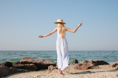 Young woman near sea on sunny day in summer, back view