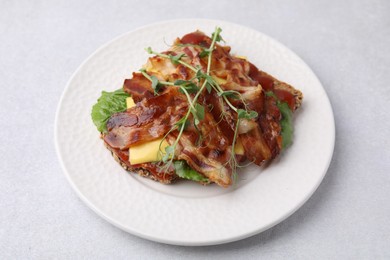 Photo of Tasty sandwich with bacon and microgreens on light grey table