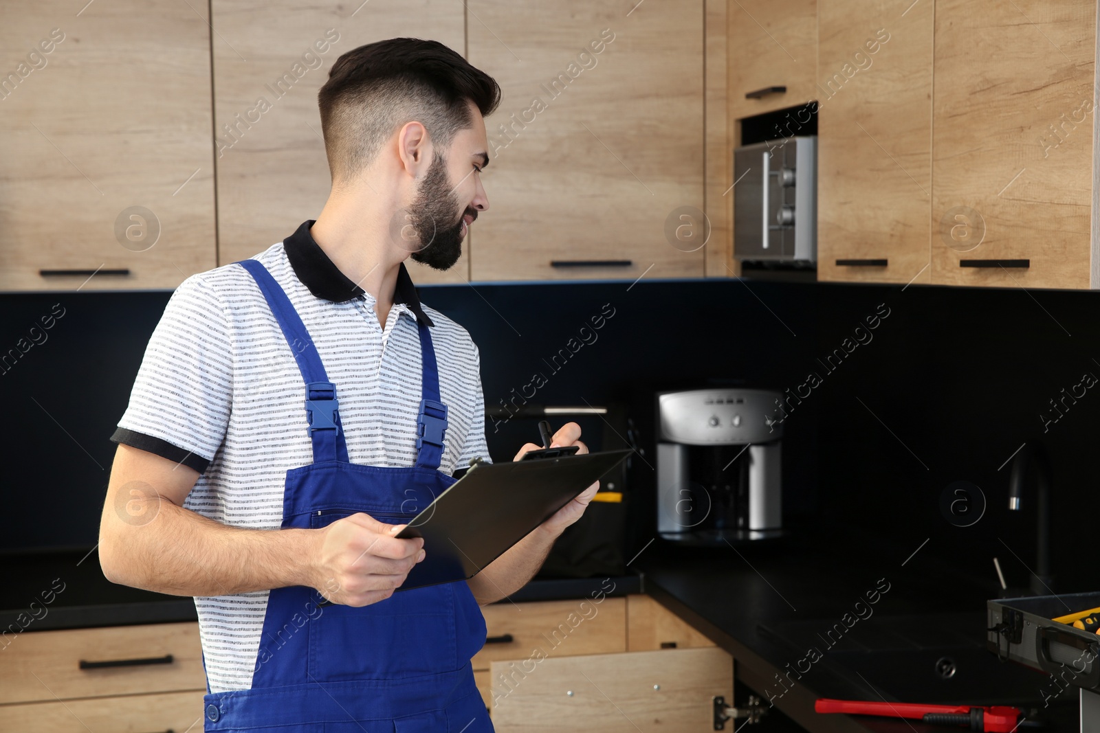 Photo of Male plumber with clipboard in kitchen. Repair service