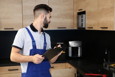 Photo of Male plumber with clipboard in kitchen. Repair service