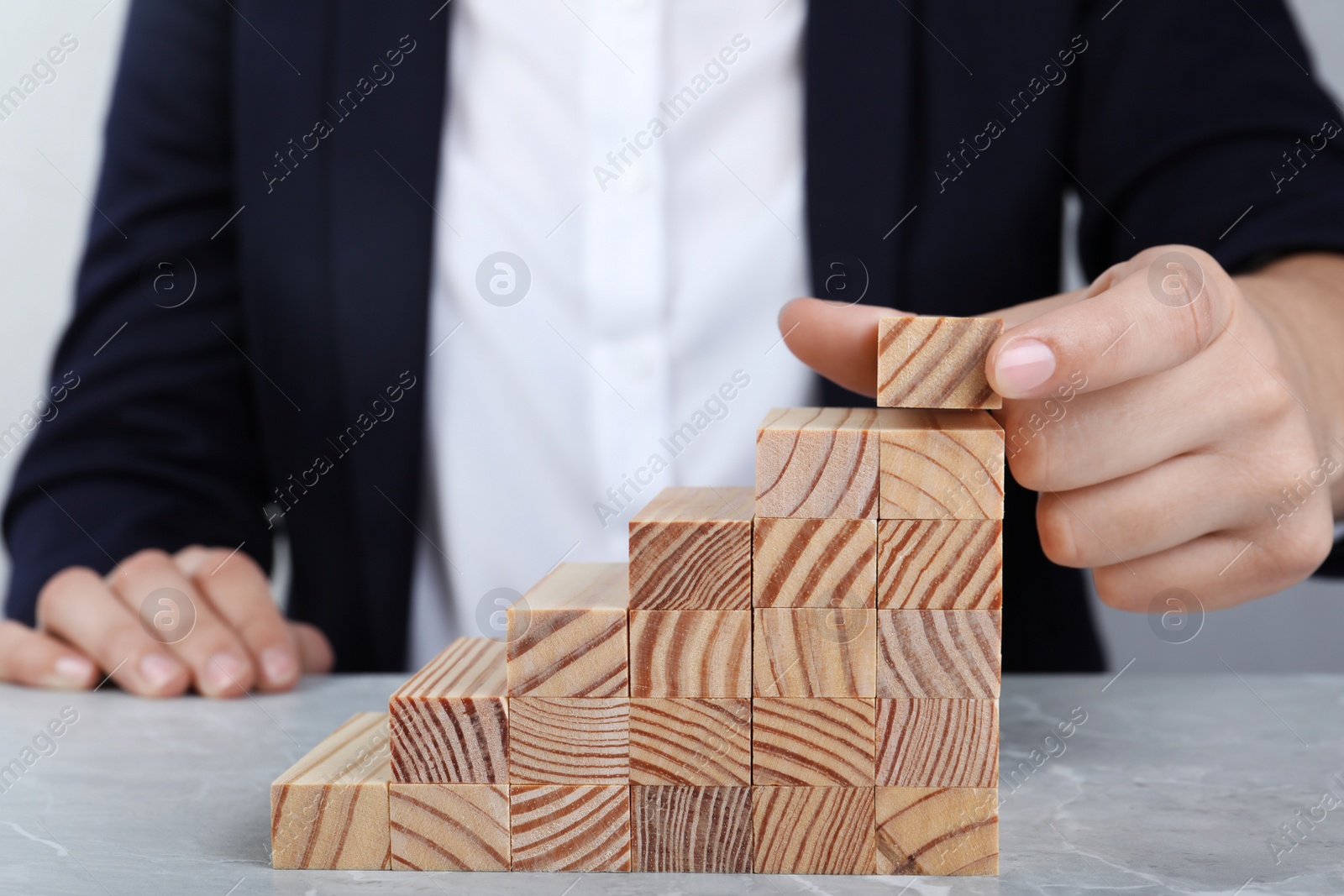Photo of Businesswoman building steps with wooden blocks at table, closeup. Career ladder